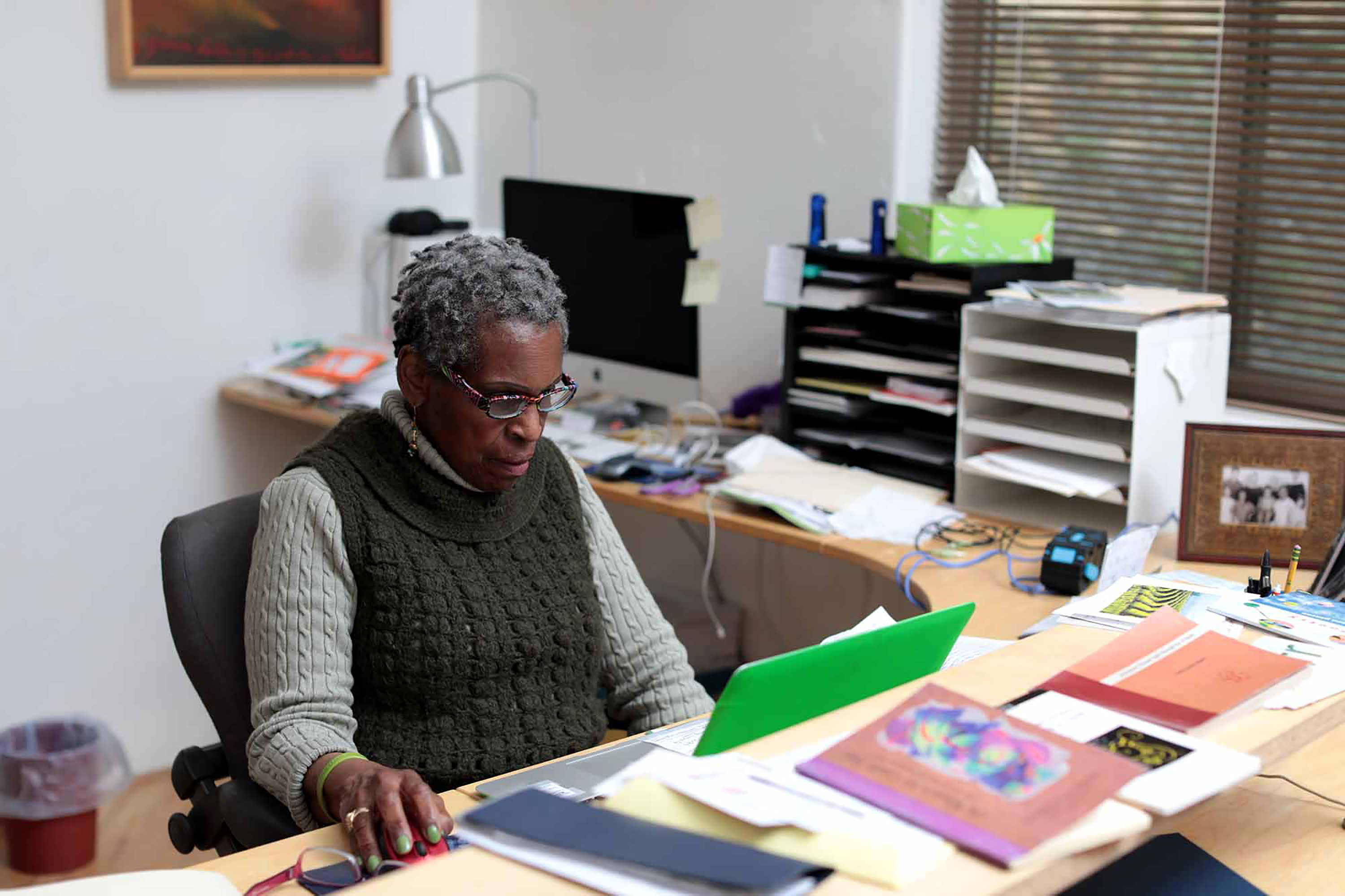 Gerda Govine Ituarte, 77, writes on her laptop in her home office. She is a poet working on her fifth book of poetry. Her husband, Carlos Luis Ituarte, 75, is a painter and sculptor. Two of his paintings are pictured. The creative couple hope to artists at their property in the future.