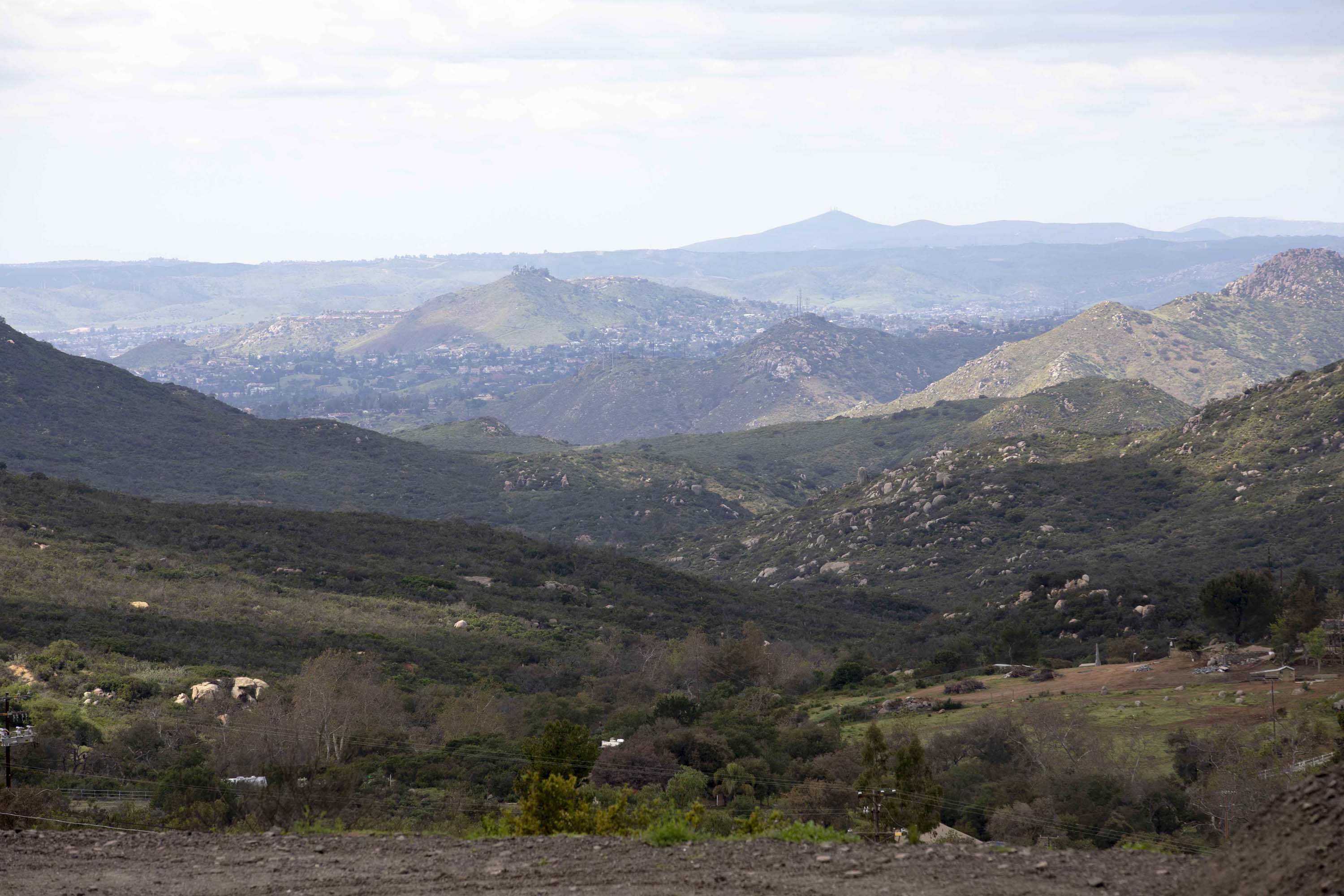 Colorful mailboxes line a dusty road in Jamul; The view from the Ituartes' mountain property overlooking San Diego in the distance.